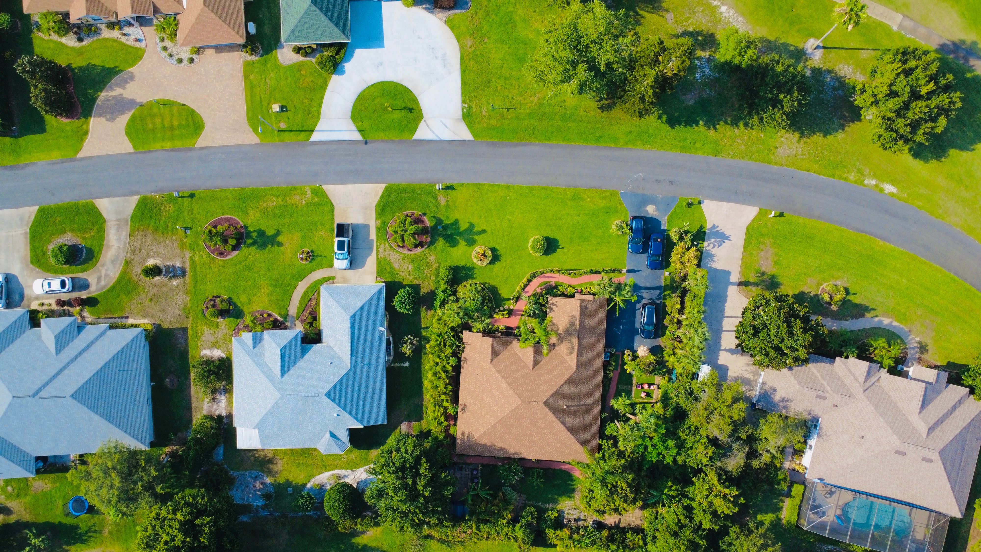 Illustrative stock photograph: Overhead view of houses, driveways, green lawns and a curved residential street.
