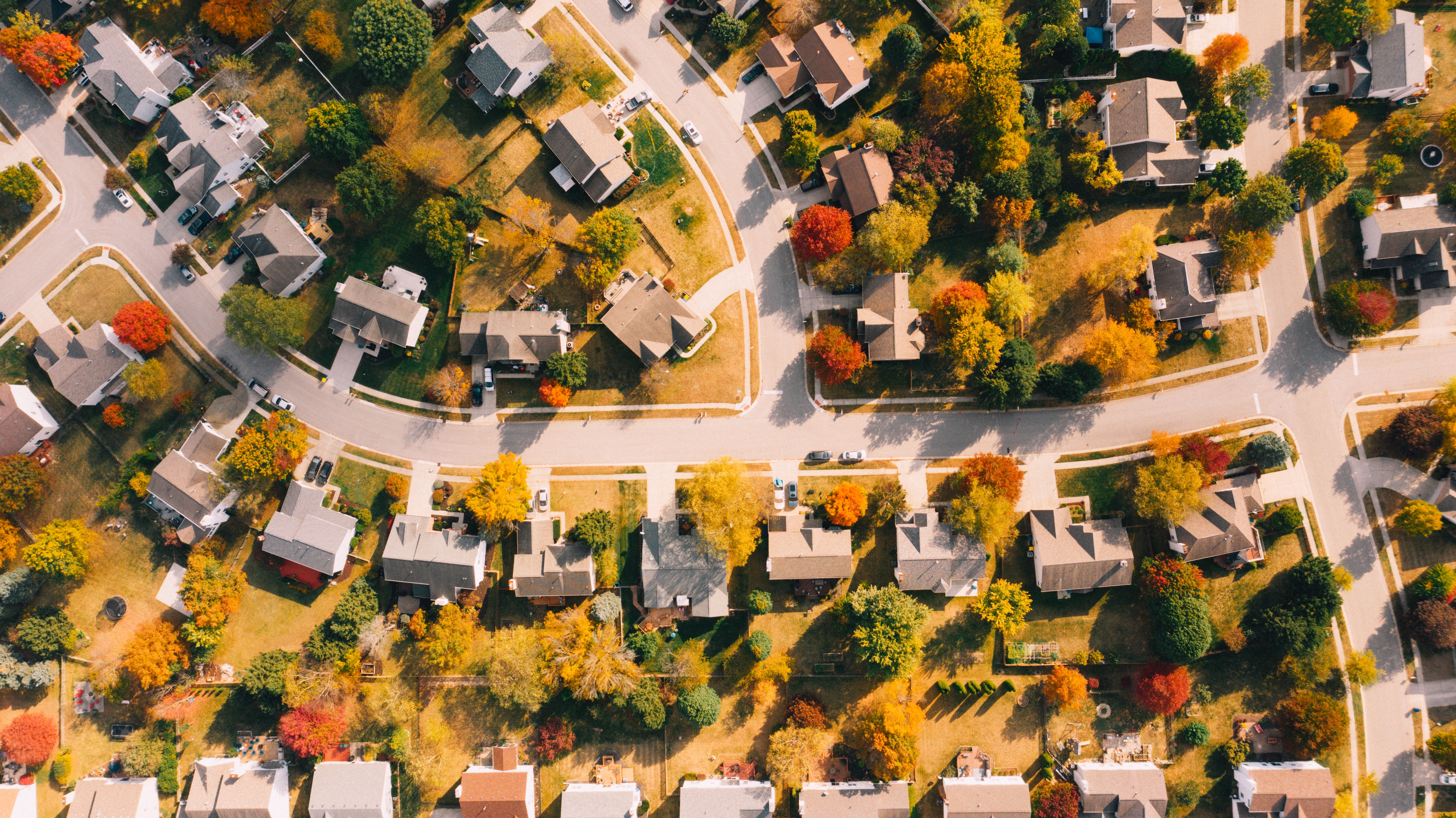 Illustrative stock photograph: Overhead view of homes, curving streets and autumn trees in a residential neighborhood.