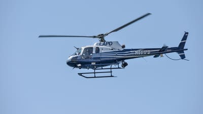 File photograph of a blue-and-white LAPD helicopter flying against a clear sky; the image does not depict the reported Tarzana incident