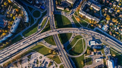 Illustrative stock photograph: Aerial view of a highway interchange, buildings, vehicles and green spaces.