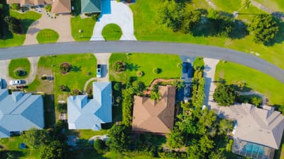 Illustrative stock photograph: Overhead view of houses, driveways, green lawns and a curved residential street.